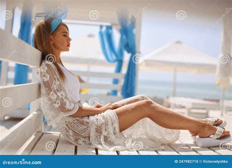 Beautiful Fashionable Girl In A White Bathing Suit Lies On A Sun Lounger Near The Beach Resting