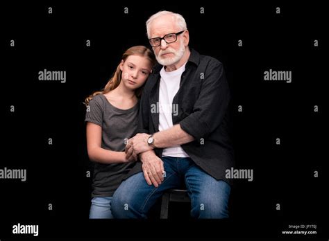 Granddaughter Leaning On Grandfathers Shoulder Isolated On Black Stock