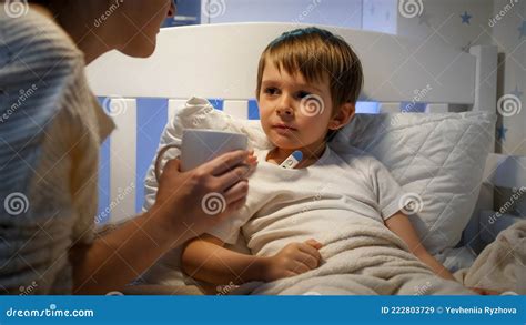 Madre Dando Té Caliente A Su Hijo Enfermo Sintiéndose Mal Tumbado En La