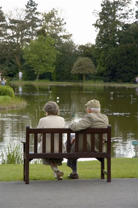 Elderly Couple An Elderly Couple Relax On A Park Bench Sponsored