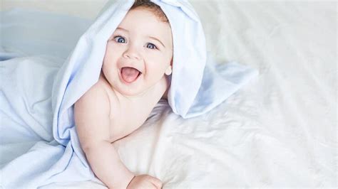 เด็กทารกแรกเกิดเด็กวัยหัดเดินนอนอยู่บนเตียงสีขาวคลุมด้วยผ้าขนหนูน่ารัก