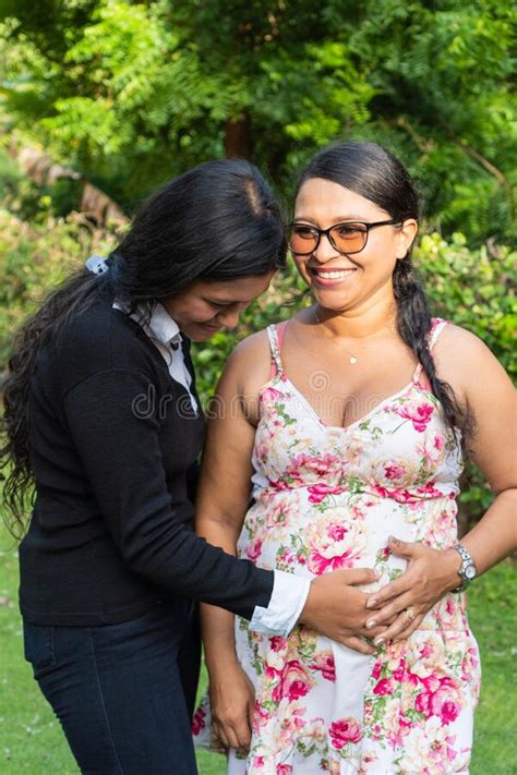 Latin Daughter Holds Her Mother`s Hands On Her Pregnant Belly Stock