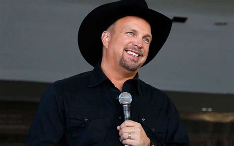 A Man Wearing A Black Hat And Holding A Microphone