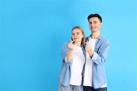 Free Photo Cute Couple With Finger Hearts On Blue Background