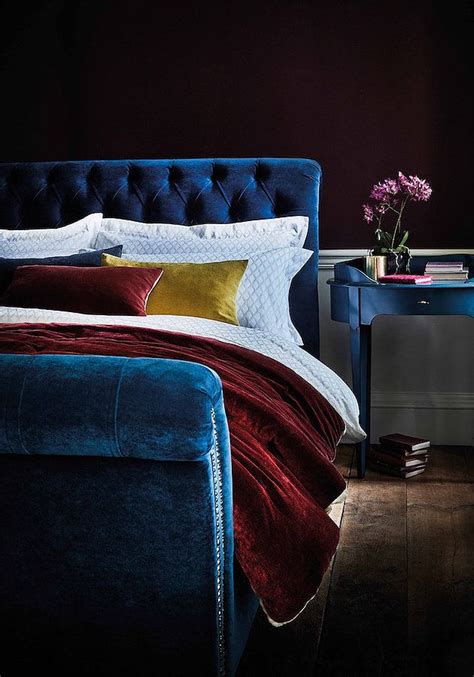 A Bed With Blue Velvet Headboard And Pillows On It Next To A Night Stand