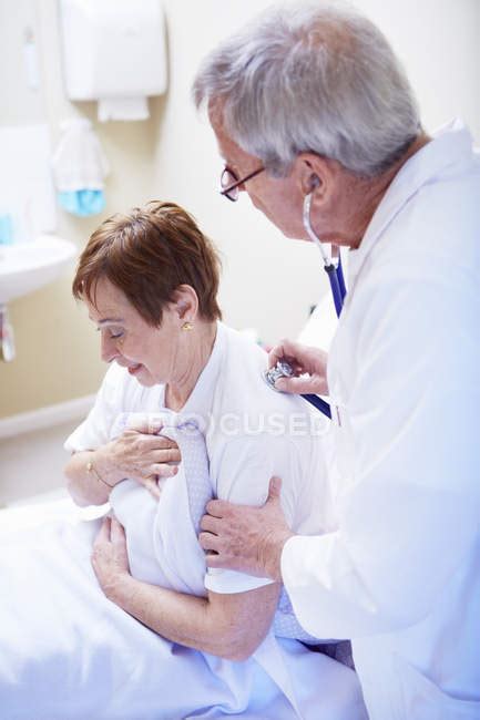 Doctor Examining Senior Woman Lying In Hospital Bed — Indoor