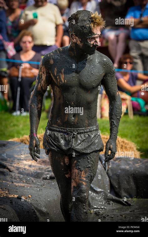 a man stands covered in mud in the mud wrestling pit at the lowland games in somerset with