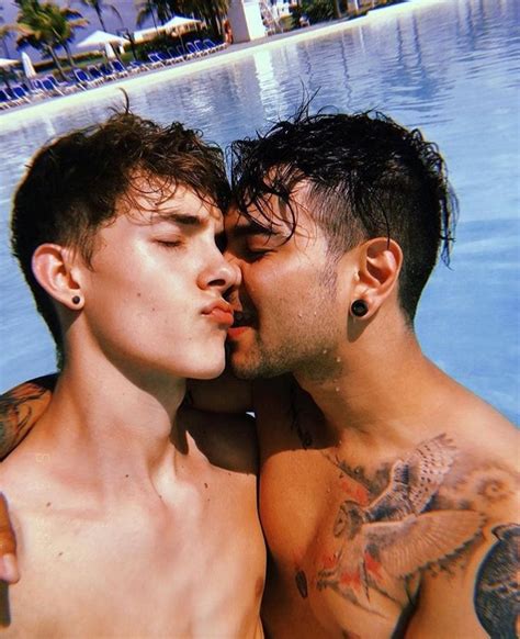 Two Men Kissing Each Other In Front Of A Pool With Blue Water And Palm