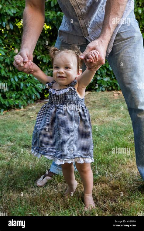 Father Helping His Nine Month Old Girl To Walk In Her Yard She Loves