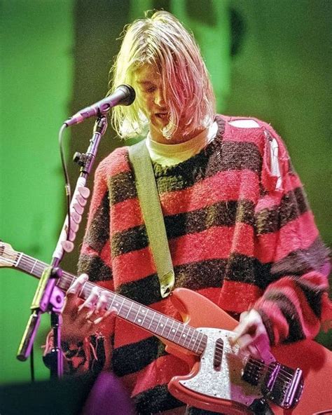 a woman with blonde hair playing guitar in front of a microphone and green screen behind her