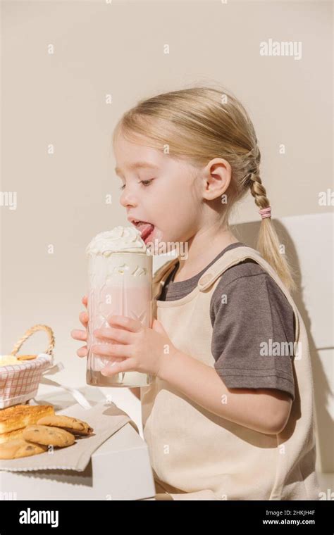 Cute Little Girl Eating Cookies With Milkshake Stock Photo Alamy