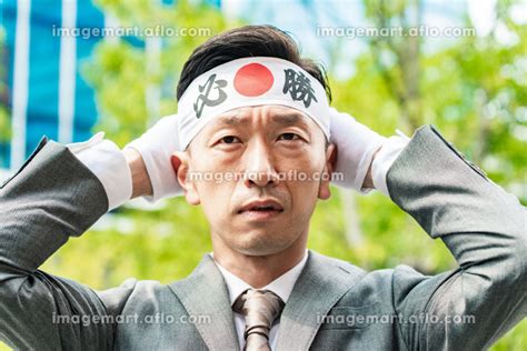 「必勝」のハチマキを頭に巻くスーツ姿の男性 166841173 ｜イメージマート