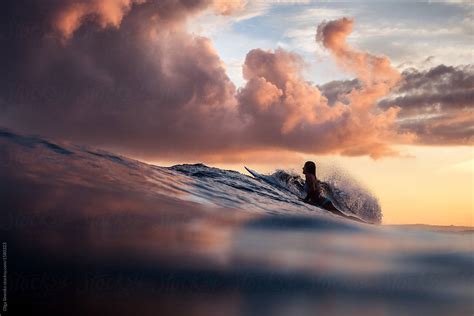Silhouette Of Woman Surfing In The Ocean At Sunset Beautiful Clouds