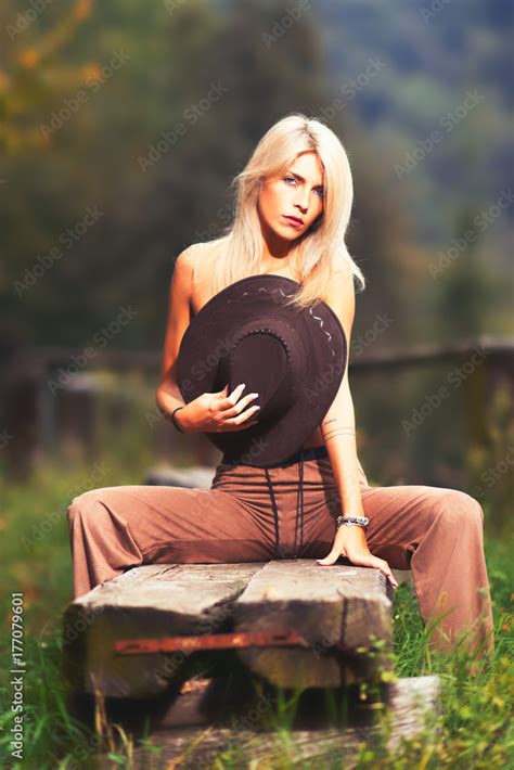 Sexy Naked Country Girl Covering Her Breast With A Cowboy Hat And Sitting On A Wooden Bench