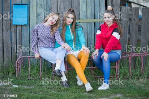Mädchen Im Stil Der Neunziger Jahre Drei Landmädchen Sitzen Auf Einer Holzbank Stockfoto Und
