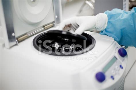 Lab Technician Inserting Sample Test Tube Into A Centrifuge Stock Photo