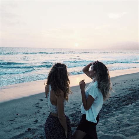 two women standing on the beach looking at the ocean