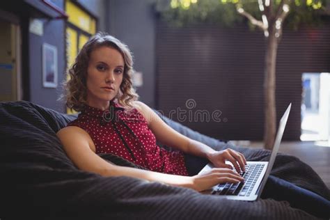 Portrait Of Confident Young Woman Sitting With Laptop On Bean Bag Stock