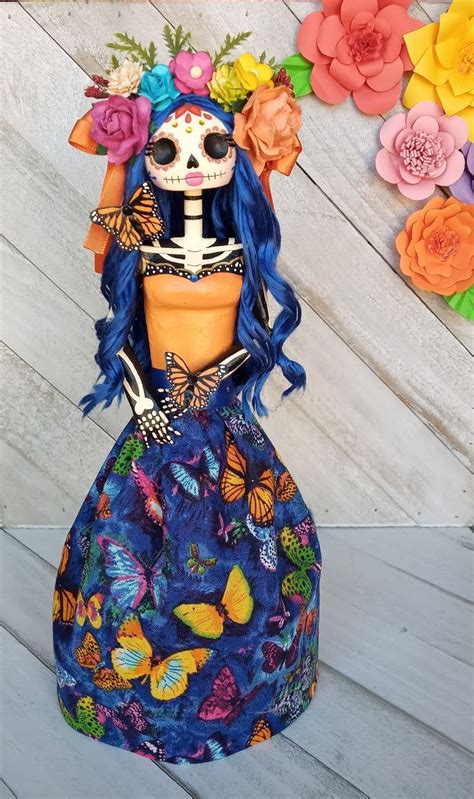 A Doll With Blue Hair And Flowers On Its Head Wearing A Dress