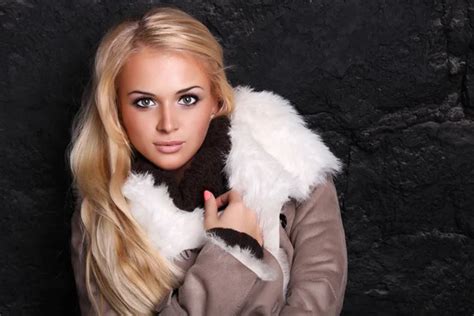 beautiful blond woman in a fur near bricks wall winter style long hair