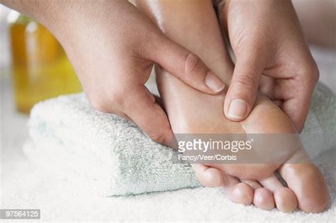 Massage Therapist Applying Pressure To Foot With Her Thumbs High Res