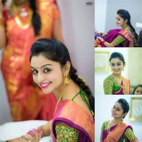 A Woman In A Green And Orange Sari With Her Hands On Her Chest Smiling