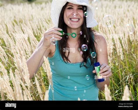 Woman Blowing Bubbles In Wheatfield Stock Photo Alamy