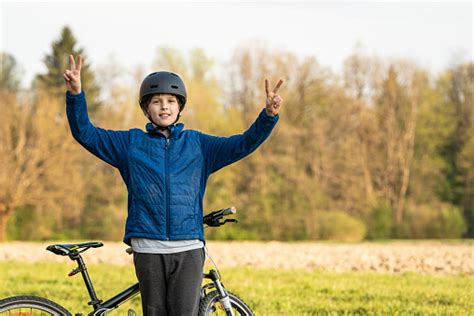 A Triumphant Child With A Black Helmet By The Bike In Nature Stock