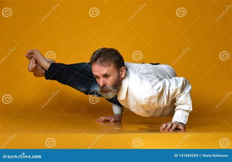 Old Man Practicing Yoga Doing Stretching Exercises Against Yellow