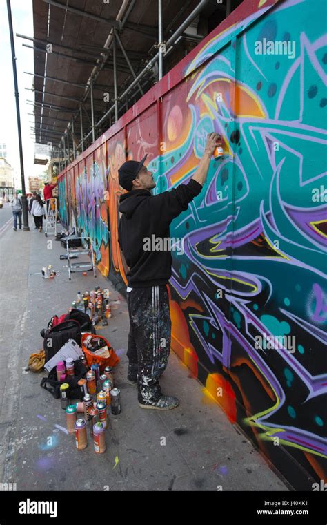 Street Artist Spray Painting Graffiti Mural On Hoarding Along Great