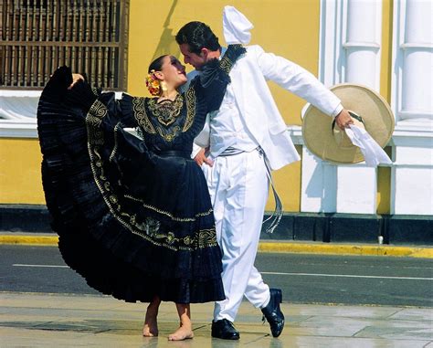 A Man And Woman Dancing On The Street In Front Of A Yellow Building