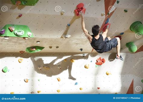 Young Man Bouldering In Indoor Climbing Gym With Clear Shadow On Wall