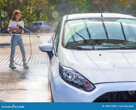 Girl Washing Car with Water and Hose at a Do it Yourself Car Wash Stock