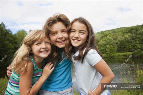 Three Girls Posing Side By Side In Front Of Forest Lake — Rural Scene