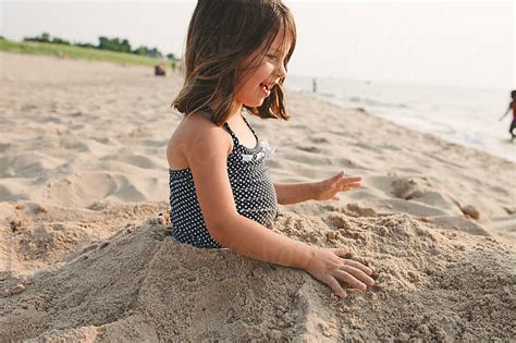 Smiling Young Girl Buried In Sand At The Beach By Amanda Worrall