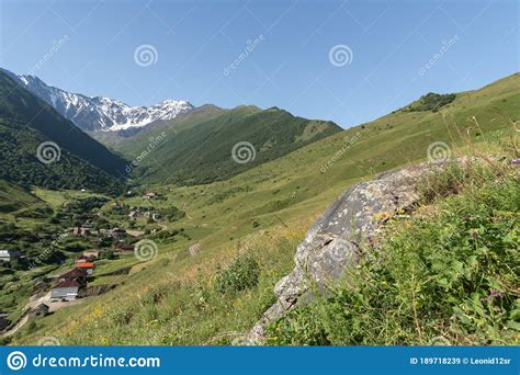 Mountain Landscape With Green Meadow And Mountain Village In Valley