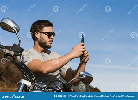 Biker Sitting On The Motorcycle Taking A Picture Of The Landscape With