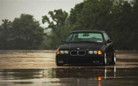 A Black Car Is Parked In The Middle Of A Flooded Area With Trees Behind It