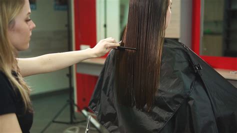 The Hairdresser Of The Beauty Salon Is Cutting Hair For The Girl Who