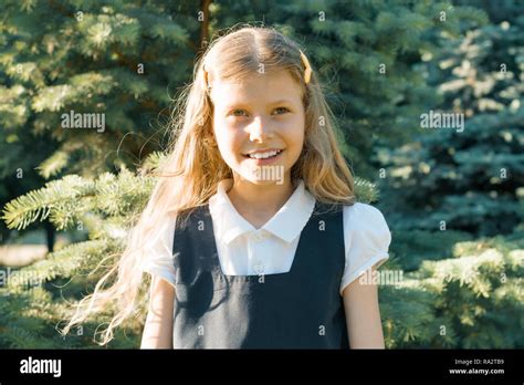 Outdoor Portrait Of A Little Beautiful Smiling Schoolgirl Blonde With Long Curly Hair In School