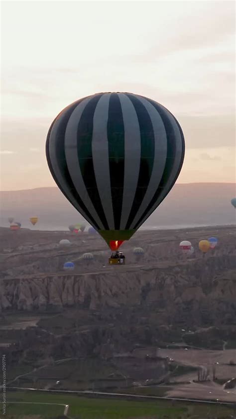 Commercial Hot Air Balloon Flying Over Rock Formations Near Goreme In