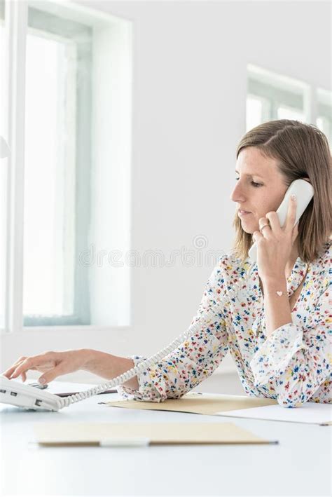 Woman Dialing A Telephone Number On White Landline Phone Stock Photo