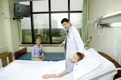 Child Lying In Hospital Bed Doctor Standing By Side Stock Photo