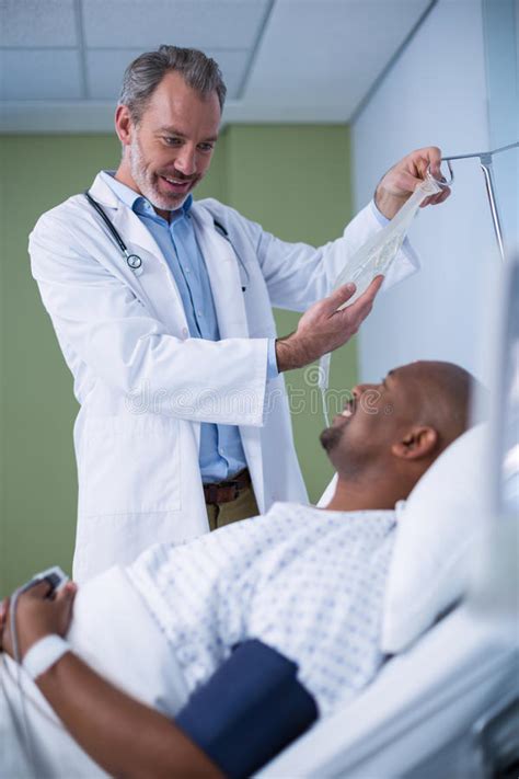 Doctor Interacting With Patient While Adjusting Iv Drip Stock Photo
