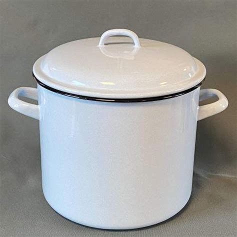 A White Casserole With Black Trim On The Rim And Lid Is Sitting On A
