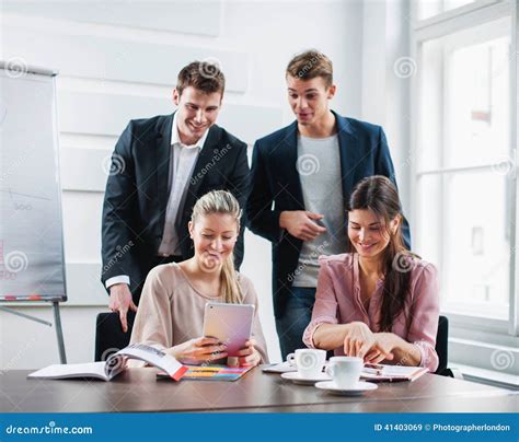 Happy Young Business People Using Tablet Pc At Desk In Office Stock