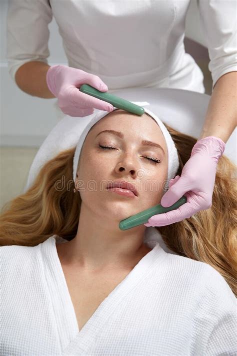 Young Woman Receiving Facial Massage With Stone Sticks In Beauty Salon Stock Image Image Of