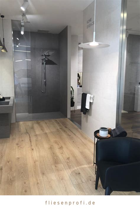 A Modern Bathroom With Wood Flooring And Gray Walls Along With A Black Chair In The Foreground
