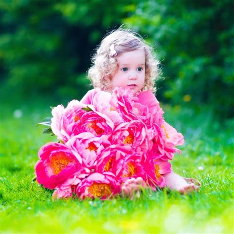 Niña Con Las Flores De La Peonía En El Jardín Foto De Archivo Imagen