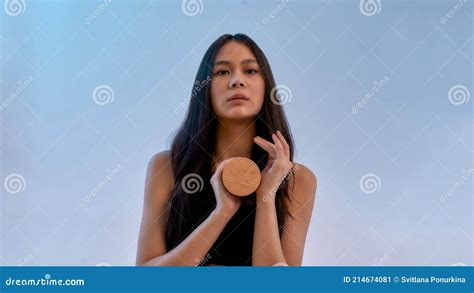 Portrait Of A Young Sensual Asian Woman Looking At Camera Holding Beauty Product While Posing